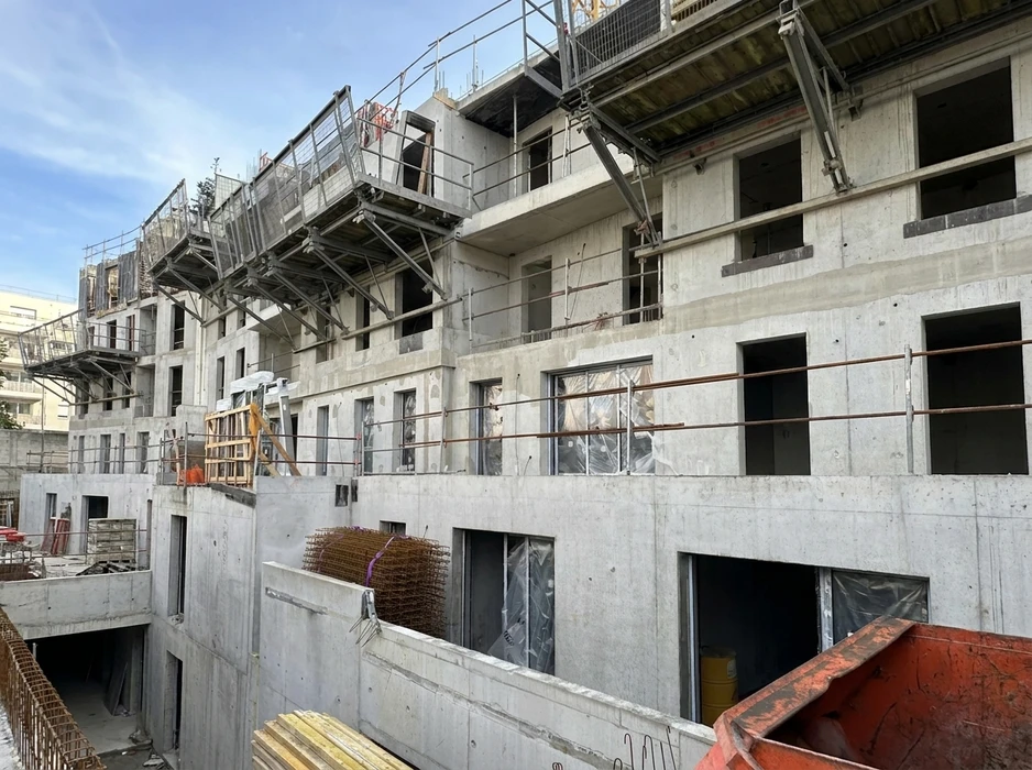 Chantier de construction en cours, vue extérieure d'un immeuble en béton brut de décoffrage, structure en R+4