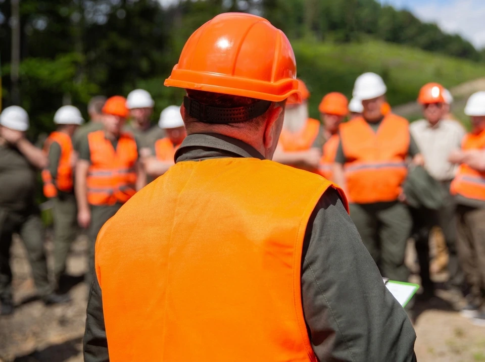 Trois professionnels de la construction en tenue de sécurité se serrant la main sur un chantier, symbolisant le travail d'équipe et la collaboration